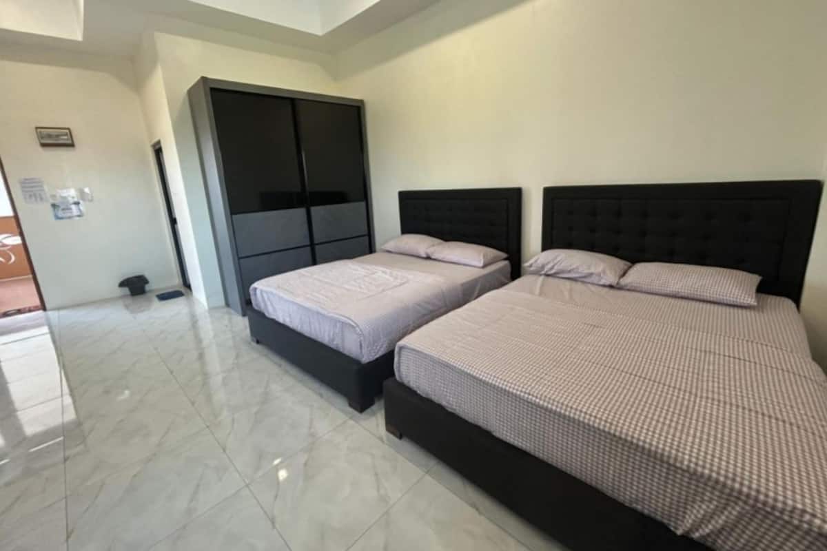 A bedroom with two beds, a wardrobe, and a tiled floor.