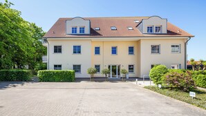 Un edificio a due piani con tetto in tegole, diverse finestre e vialetto lastricato.