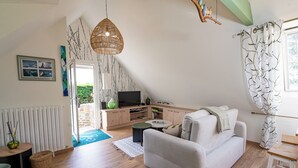 A modern living room with a sofa, a TV, and a dining area. - Description (Pléhédel)