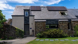 A stone building with a sloped roof, a small window, and a door. - Description (Pléhédel)