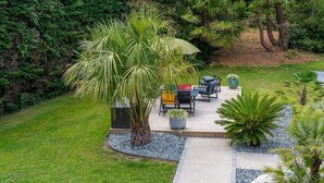 A patio with outdoor furniture and a palm tree. - Description (Pléhédel)