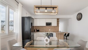 Una cocina moderna con armarios blancos, un refrigerador negro y una encimera de madera.