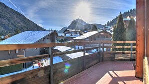 Ein Holzbalkon mit Blick auf einen Berg und ein Dorf.