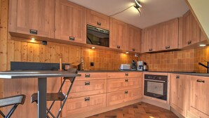 Eine Küche mit Holzausstattung, Fliesenboden und modernen Geräten.