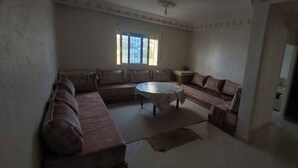 Una sala de estar con un sofá modular, una mesa de centro redonda y un ventanal con rejas decorativas.