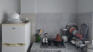 Una cocina compacta con refrigerador, estufa a gas y escurreplatos.