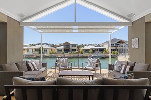 A covered outdoor seating area with a view of a marina and houses. - Mandurah Canal Escape | 5BR Home with Jetty (Dudley Park)