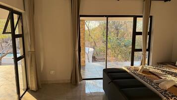 A bedroom with a large bed, a sofa, and a sliding glass door leading to an outdoor area.