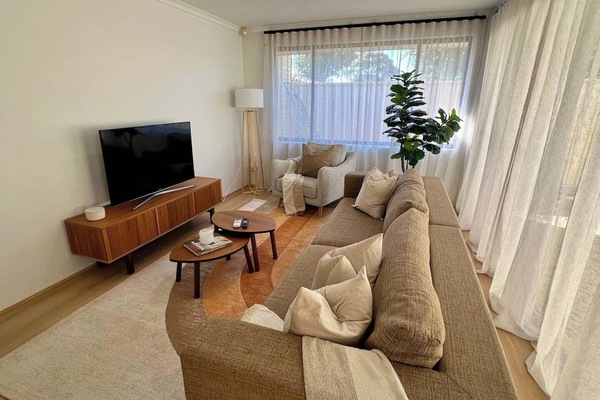 Relax in this bright, open-plan living area featuring a large, cozy sofa, a wide-screen TV for movie nights