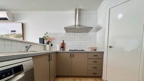 Eine kleine Küche mit Geschirrspüler, Herd und weiß gefliestem Fliesenspiegel.