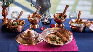 A traditional meal setup with copper dishes and a teapot on a blue tablecloth. - The Villa Himalaya (Srinagar)