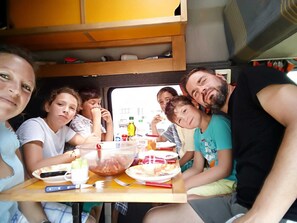 Eine Gruppe von Personen sitzt an einem Tisch mit Speisen und Getränken in einem Fahrzeug.