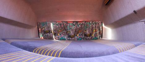 A room with a bed, a colorful tapestry, and a small wooden object on the wall.