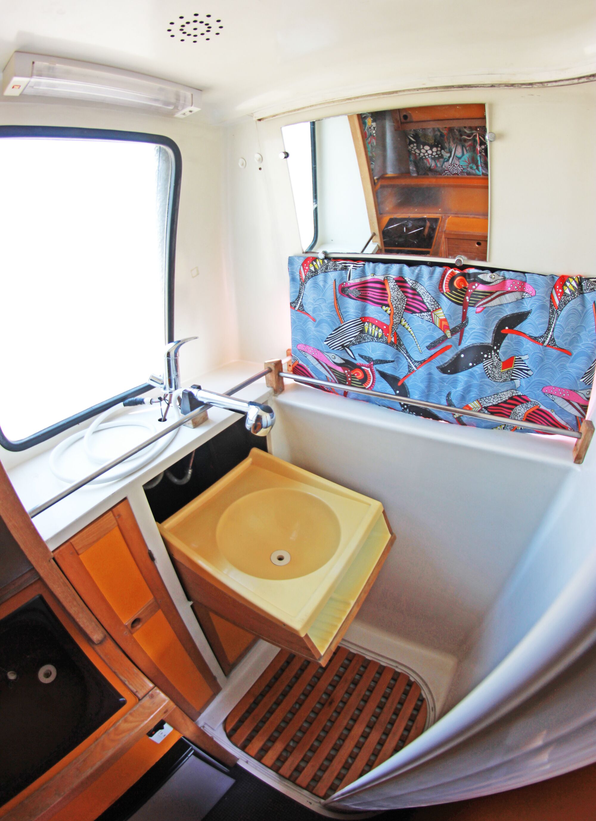 Een kleine badkamer met raam, wastafel en douche.