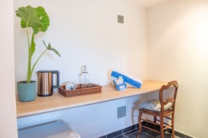 A room with a wooden counter, a potted plant, a kettle, a glass bottle, a woven basket, and a rolled towel. - 3 chambres privées avec panorama sur le Morne (Grande Riviere Noire)