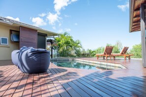A poolside area with a wooden deck, lounge chairs, and a blue bean bag. - 3 chambres privées avec panorama sur le Morne (Grande Riviere Noire)