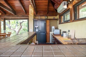 Una cocina con refrigerador integrado, cafetera y ventana con vista a follaje.