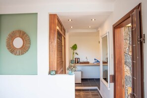 A hallway with a wooden door, a mirror, and a plant. - 3 chambres privées avec panorama sur le Morne (Grande Riviere Noire)