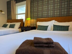 A hotel room with two beds, a nightstand, a lamp, and a window with curtains. - CHIC OASIS - Pool - Games - Pet friendly, 15 mins to Fort Bening (Columbus)