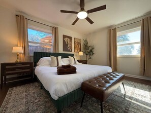 A bedroom with a bed, a bench, a nightstand, a lamp, a ceiling fan, and a window with curtains. - CHIC OASIS - Pool - Games - Pet friendly, 15 mins to Fort Bening (Columbus)