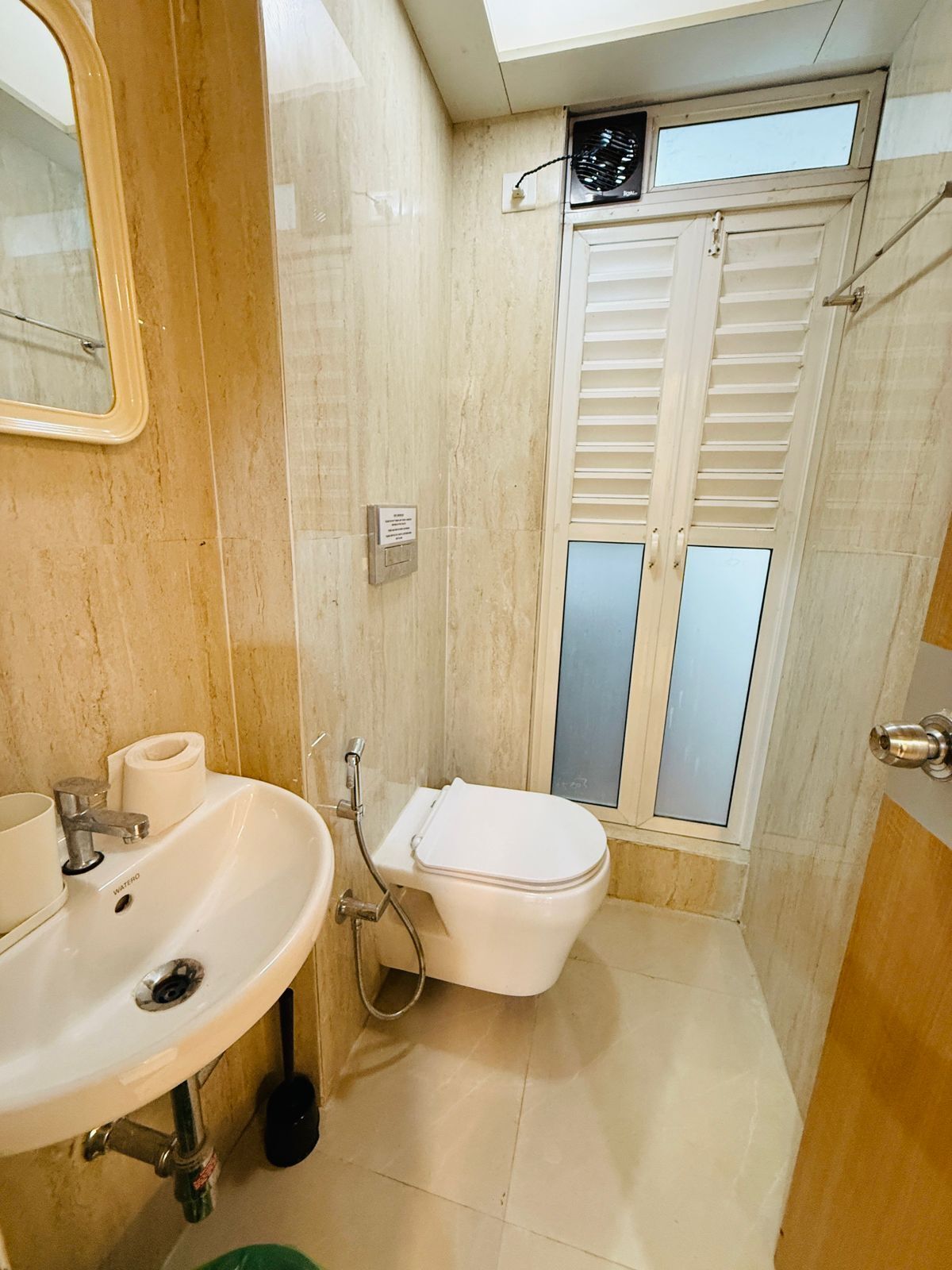 Une petite salle de bain avec un lavabo, des toilettes et une fenêtre avec des stores.