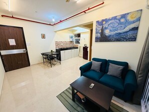 Ein Wohnzimmer mit einem türkisfarbenen Sofa, einem Couchtisch und einem Bild einer Nachtlandschaft.