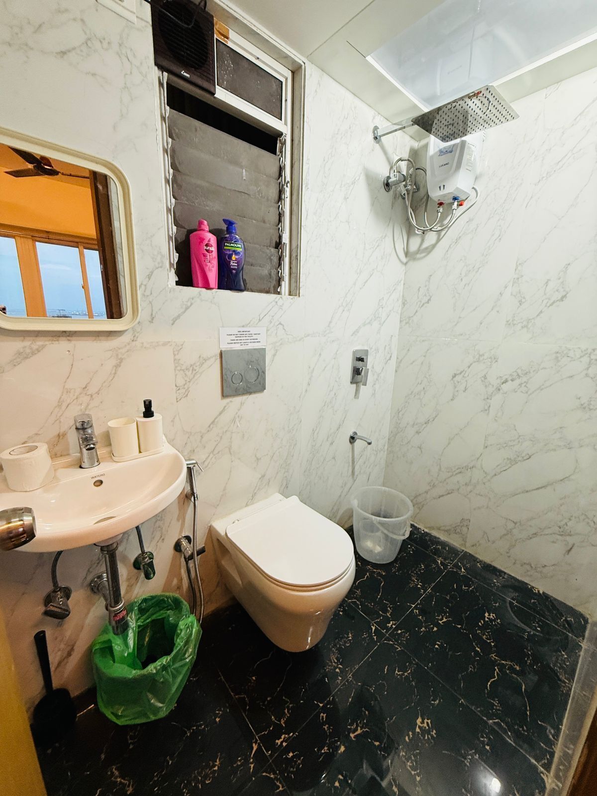 A bathroom with a white toilet, a sink with a mirror, and a shower head.
