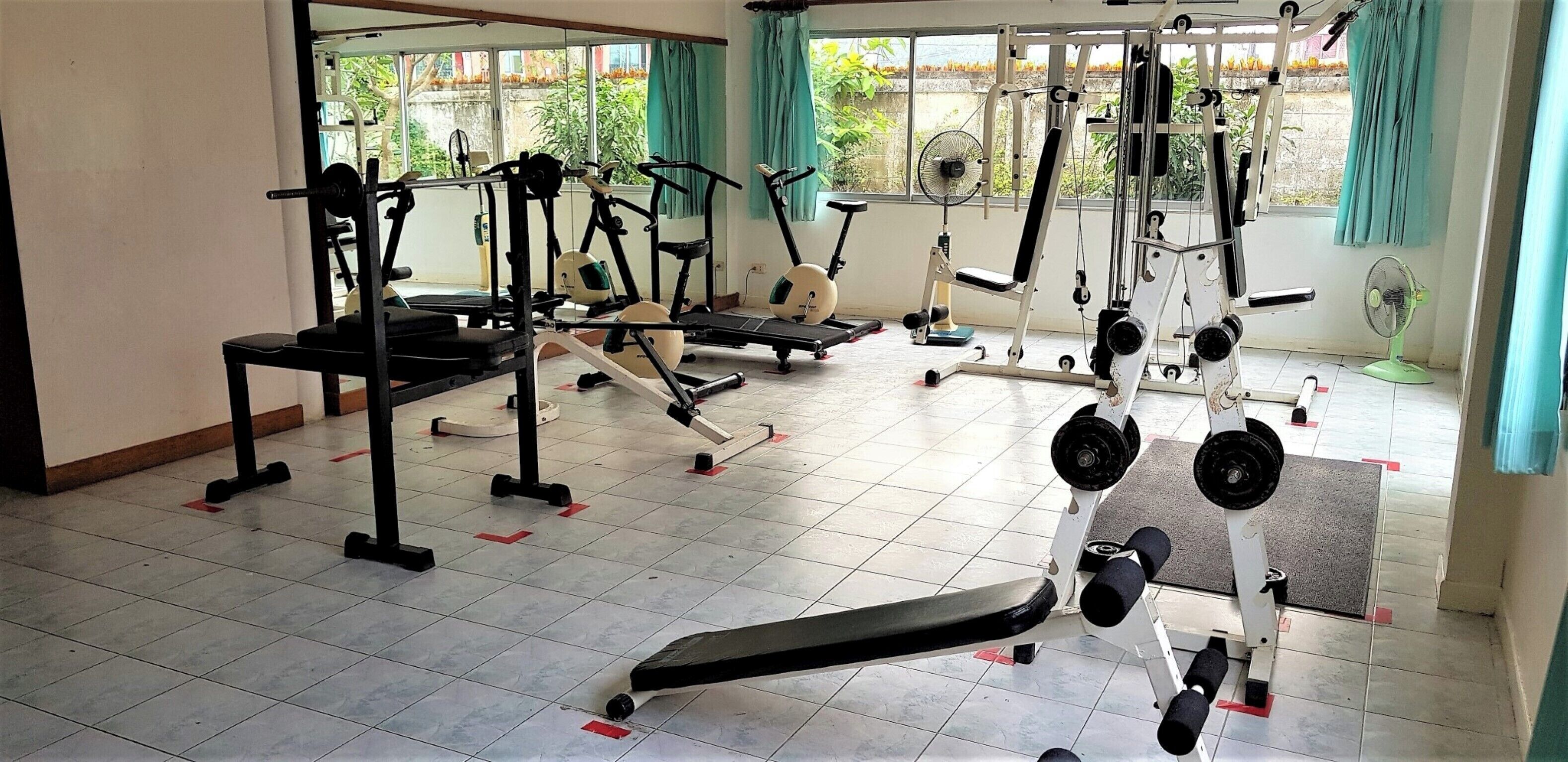 A gym with various exercise equipment, including treadmills, weight machines, and free weights.
