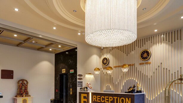Un área de recepción con suelo de mármol, una araña de cristal y un mostrador de recepción con la etiqueta "RECEPTION".