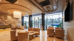 Un área de recepción moderna con un mostrador, asientos cómodos y ventanas amplias que ofrecen vistas al exterior.