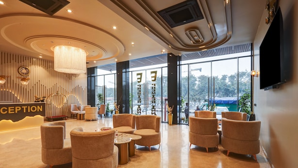 A modern reception area with a reception desk, comfortable seating, and large windows offering a view of the outdoors. - Hotel Premier Inn (New Delhi)