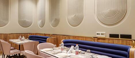 A restaurant with booths and tables, marble flooring, and a ceiling with recessed lighting.