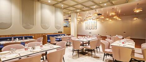 A modern restaurant interior with booths and tables, marble flooring, and pendant lighting.