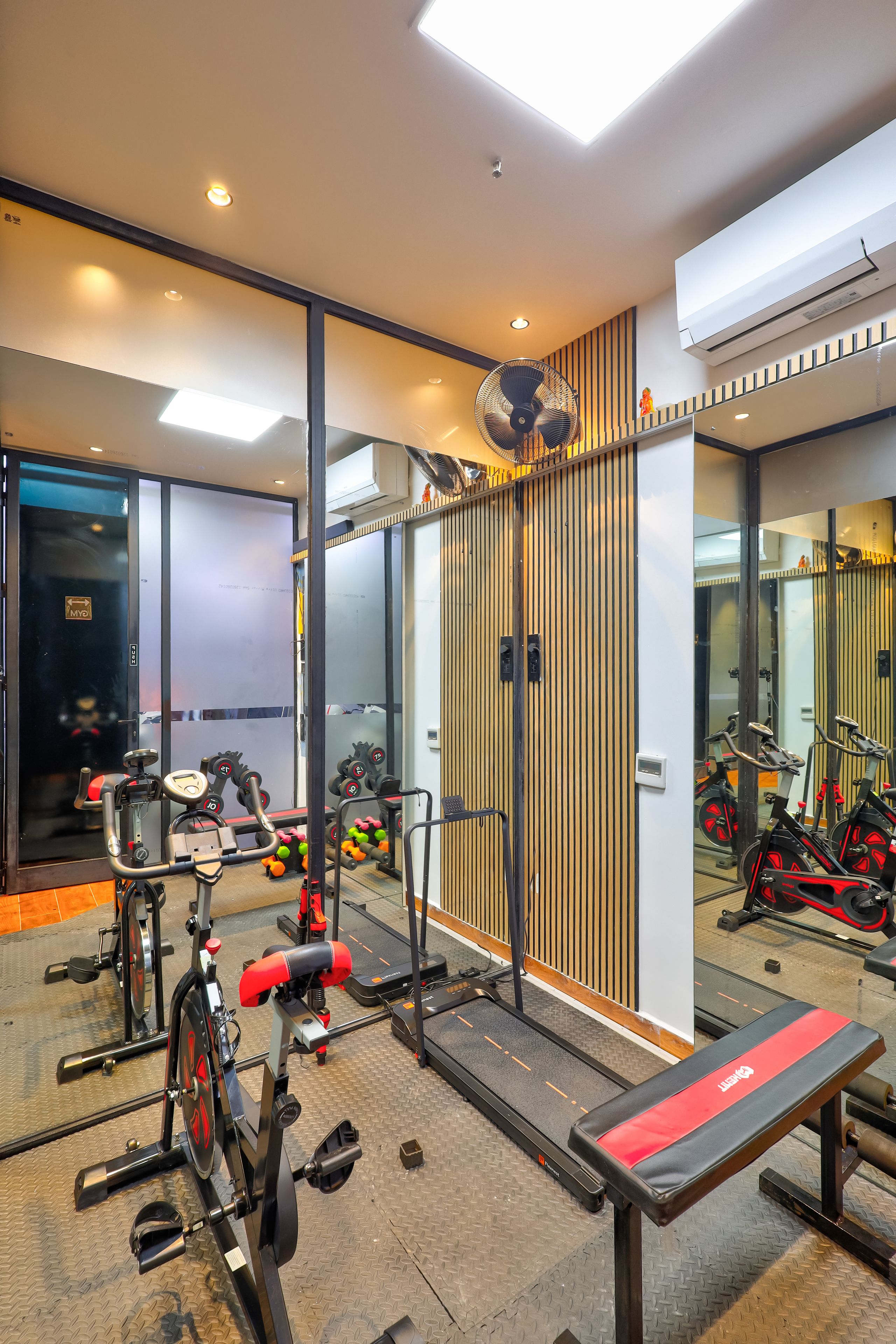 A gym with exercise equipment, a treadmill, and a mirrored wall.