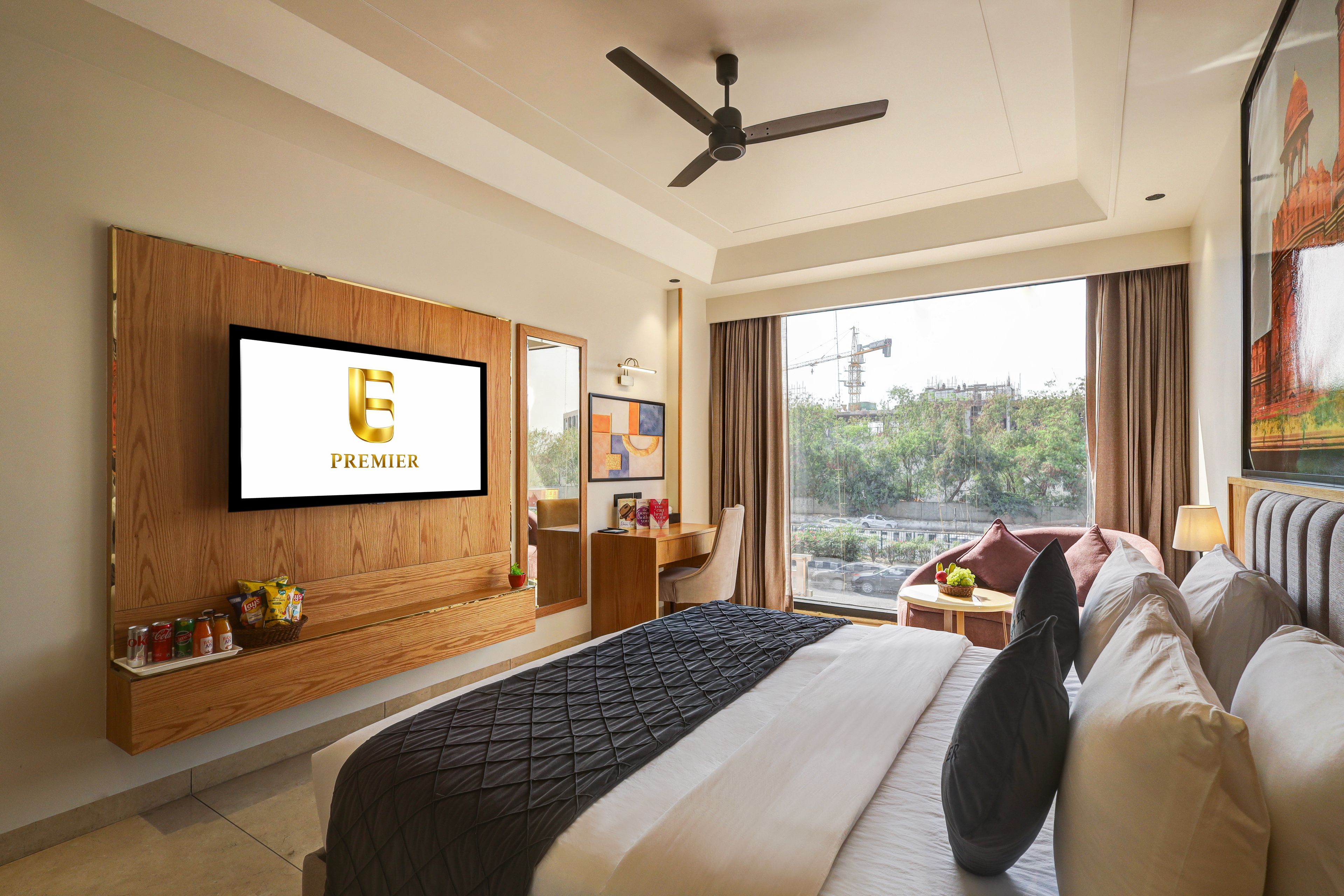Habitación de hotel con una cama grande, televisión montada en la pared, ventilador de techo y ventana con vistas al exterior.