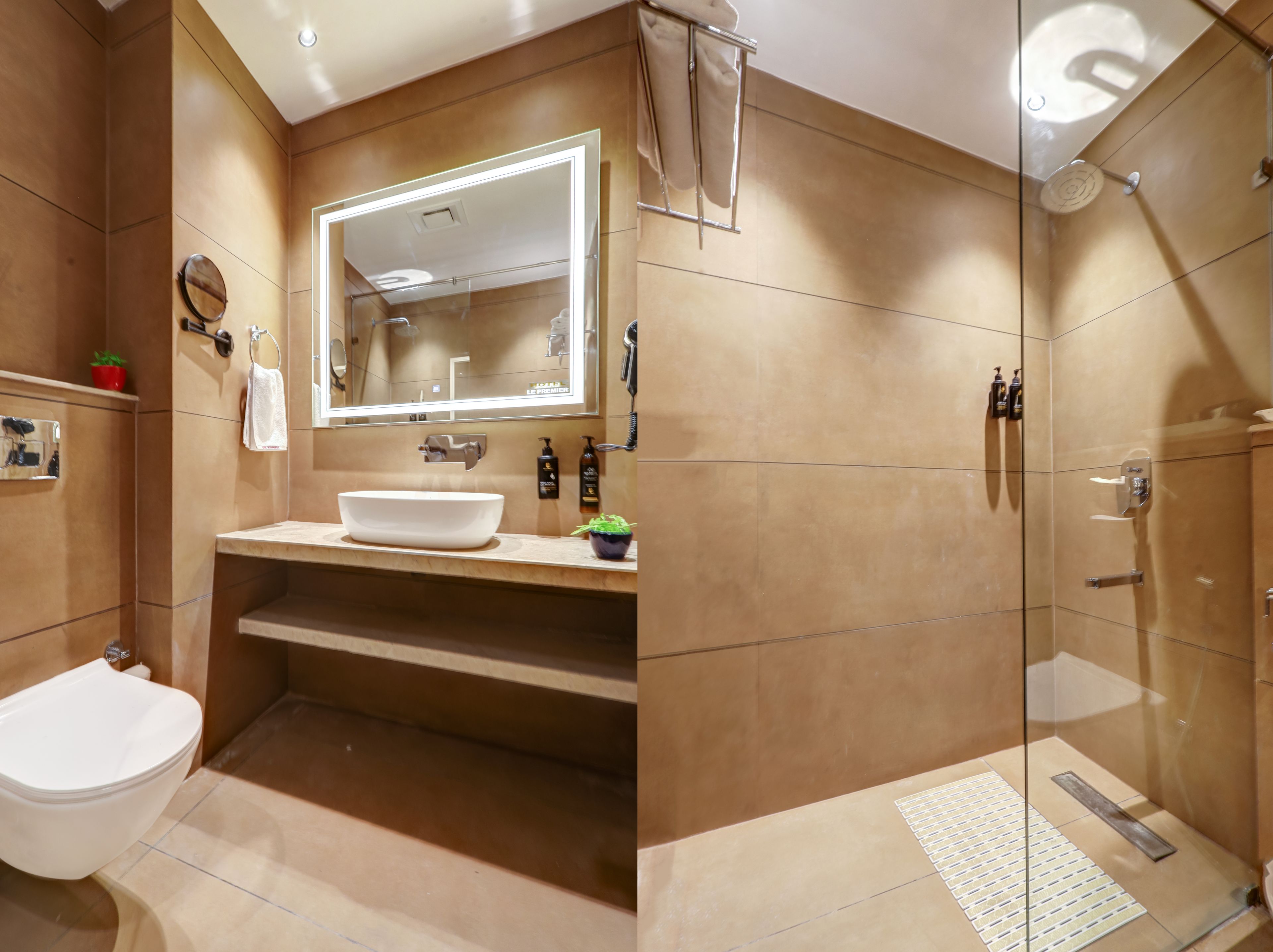 A modern bathroom with a large mirror, a sink, a toilet, and a glass-enclosed shower area.