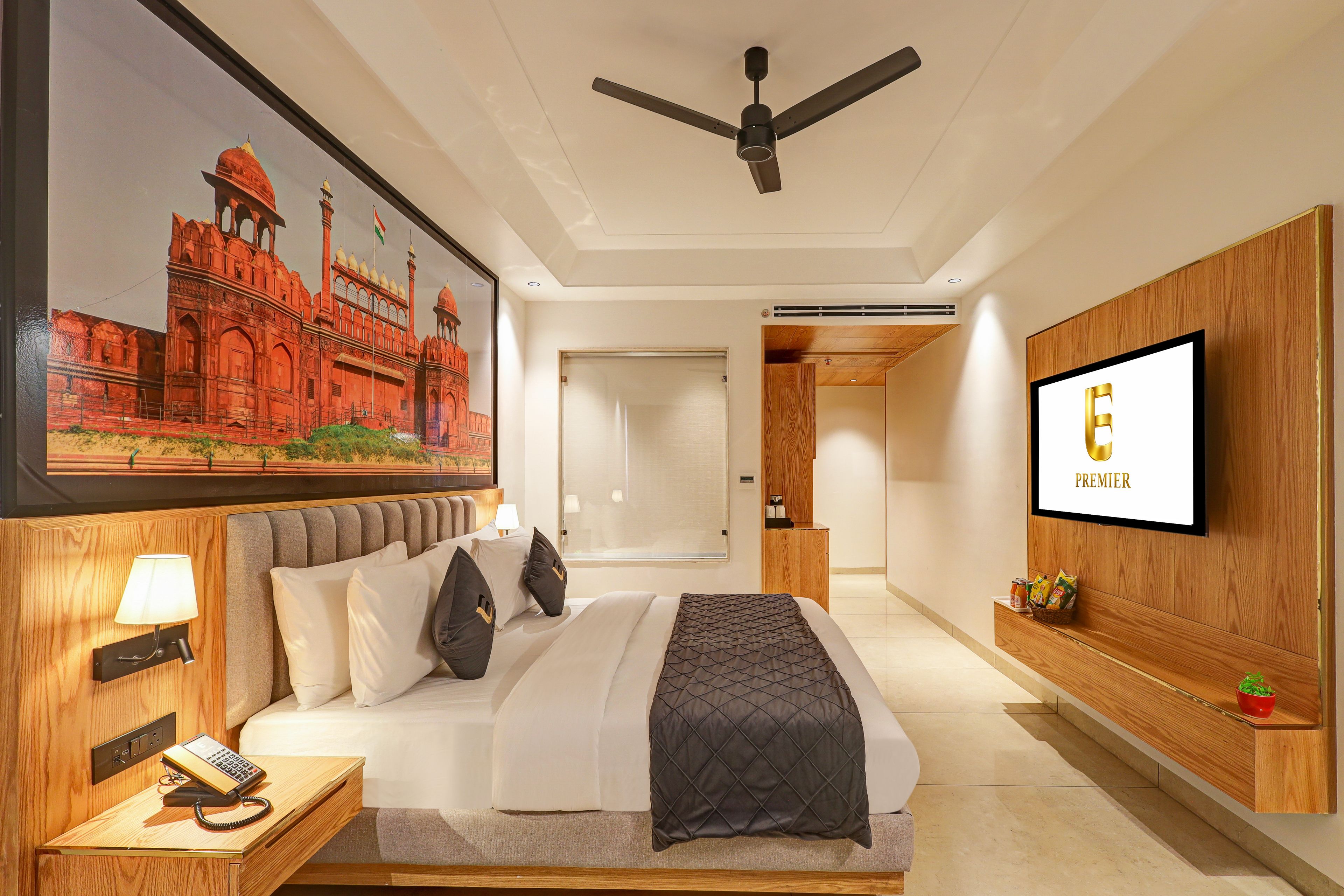 Ein Hotelzimmer mit einem Bett, einem Deckenventilator, einem Fernseher und einem Gemälde eines historischen Gebäudes.