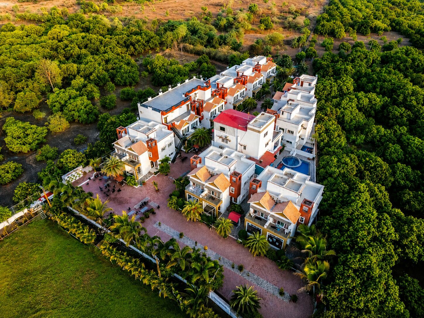 An aerial view of a residential complex with multiple buildings, a central courtyard, and surrounding greenery.