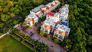 An aerial view of a residential complex with multiple buildings, a central courtyard, and surrounding greenery. - Aranya Villa Sasan Gir (Talala)