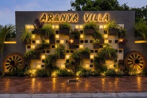 A sign for Aranya Villa with a modern design, featuring illuminated letters and planters with greenery. - Aranya Villa Sasan Gir (Talala)