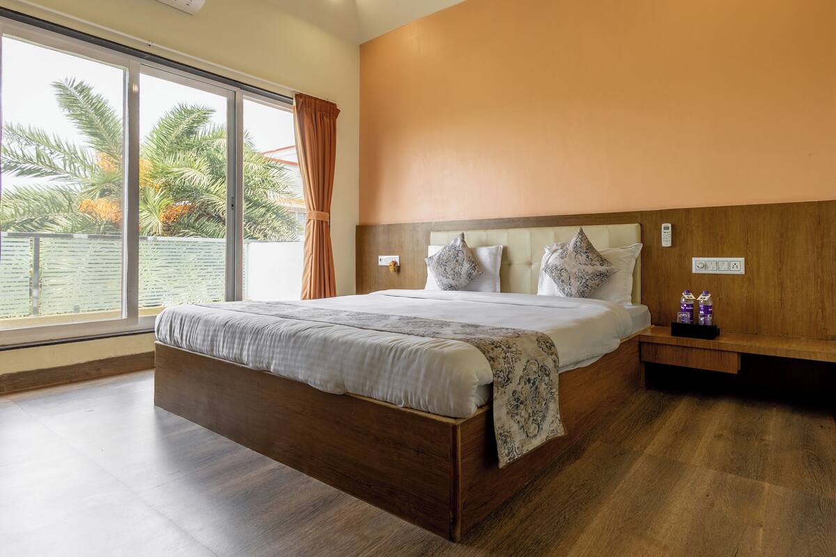 Ein Schlafzimmer mit einem großen Bett, einem Holzkopfende und Blick auf Palmen durch das Fenster.