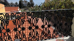 A balcony with a view of the sea, a glass of red wine, and a patterned floor. - 3-bedroom house in Bananeiras in the center of Funchal (Funchal)