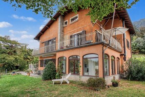 Ein zweistöckiges Haus mit Balkon, großen Fenstern und einem Garten.
