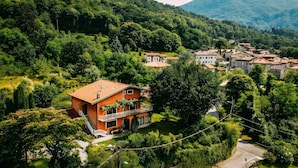 A hillside village with traditional houses, a prominent orange building with a balcony, and lush greenery. - Casa Paradiso in Porto Valtravaglia (Porto Valtravaglia)