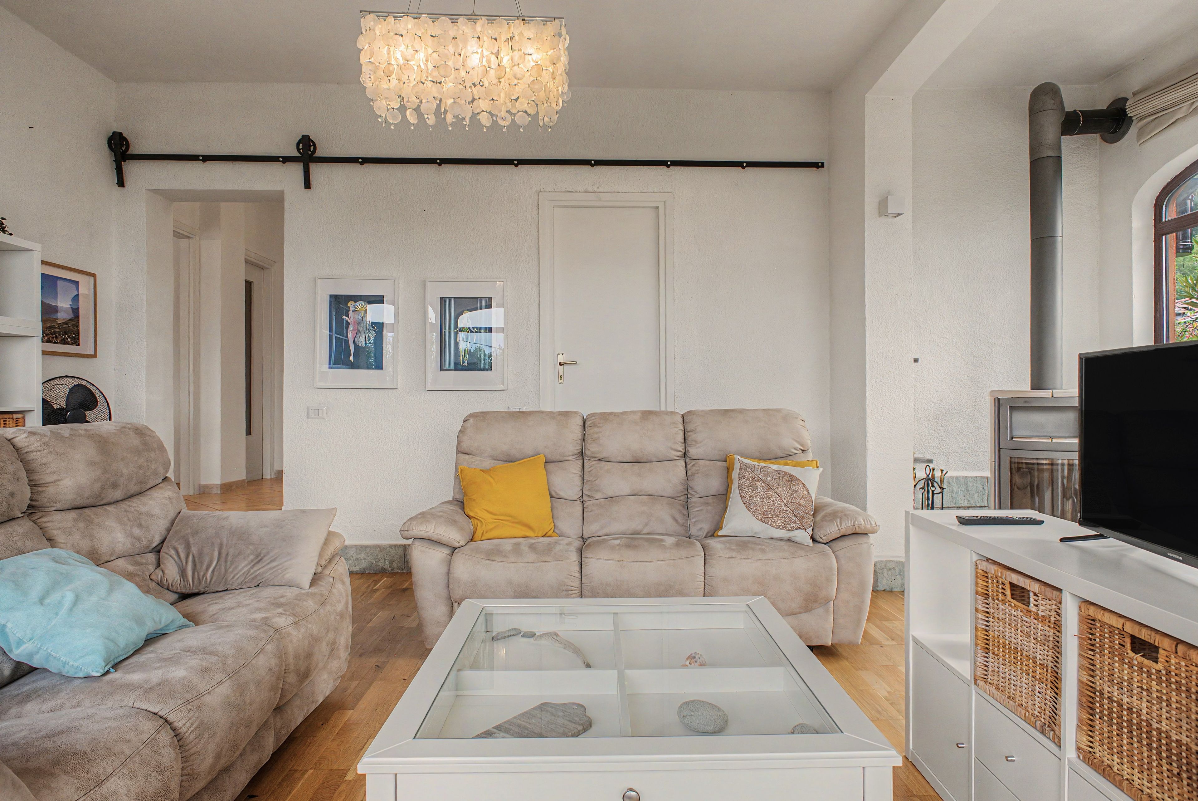 Un salon comprenant un canapé, une table basse avec un plateau en verre, un téléviseur et des œuvres d’art encadrées accrochées au mur.