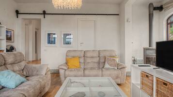 Un salon comprenant un canapé, une table basse avec un plateau en verre, un téléviseur et des œuvres d’art encadrées accrochées au mur.