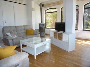 Un salon comprenant un canapé, une table basse, un téléviseur et un meuble.