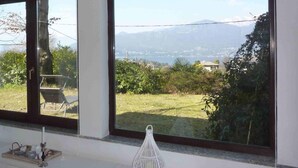 A room with large windows, a chair, a table with a candle, and a white decorative object. - Casa Paradiso in Porto Valtravaglia (Porto Valtravaglia)