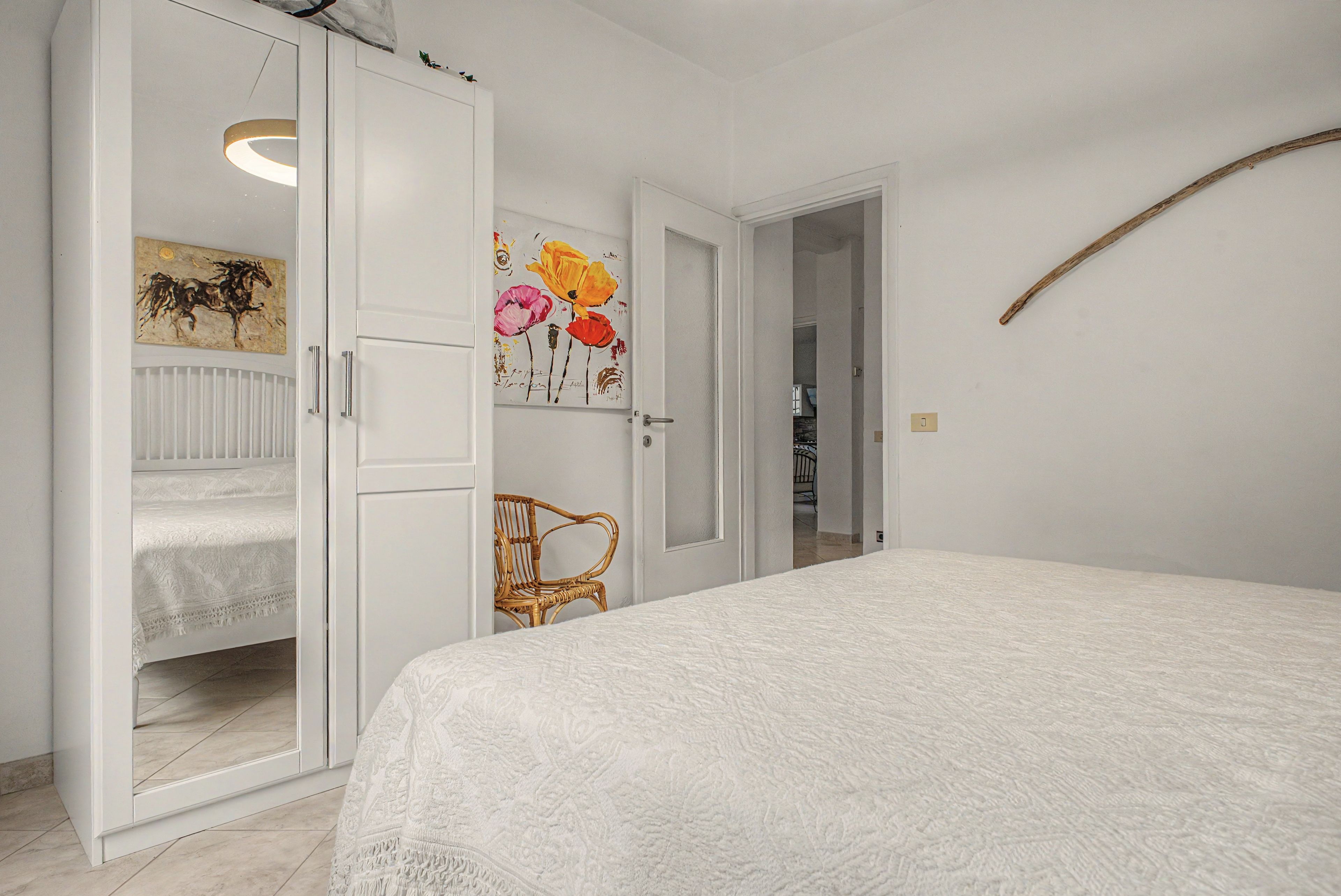 Une chambre à coucher comprenant un lit, une armoire, une chaise et une porte donnant sur une autre pièce.