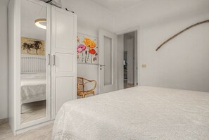 A bedroom with a bed, a wardrobe, a chair, and a door leading to another room. - Casa Paradiso in Porto Valtravaglia (Porto Valtravaglia)